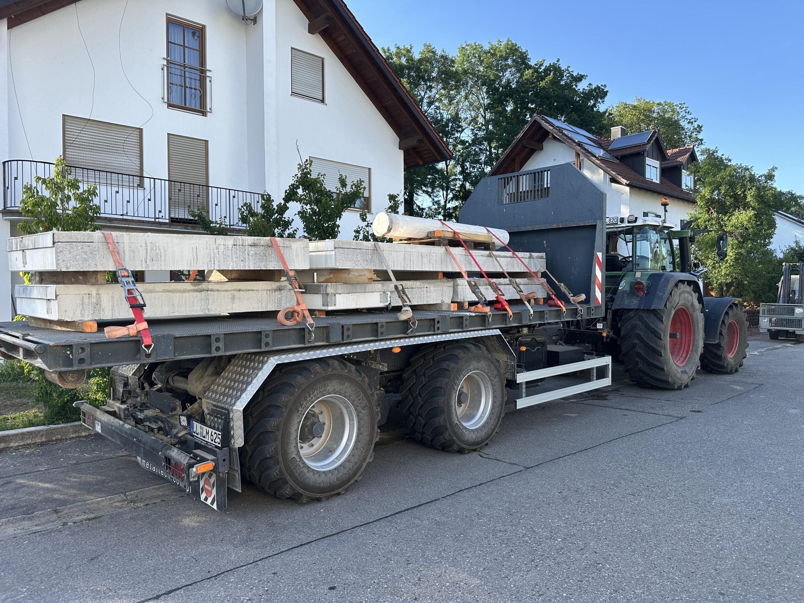 Bagger reißt Gebäude ein, Arbeiter geht durch Trümmer.